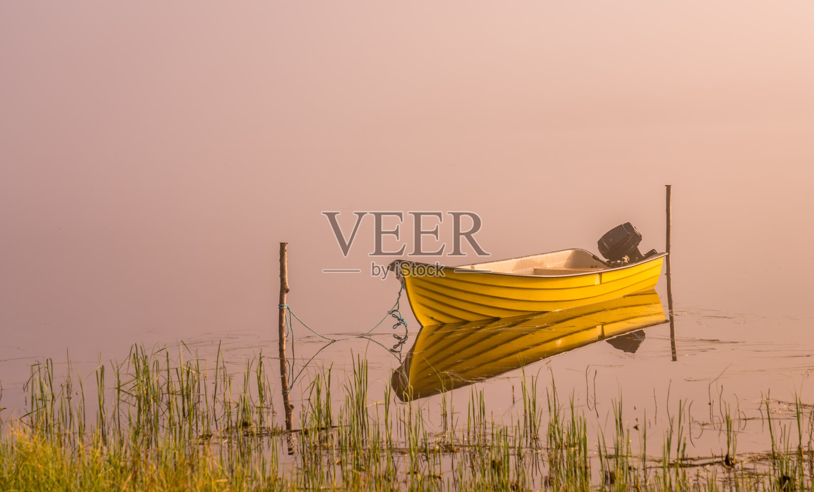 一艘小摩托艇，美丽的金色阳光透过浓雾照耀在初升的湖面上，平静的水面照片摄影图片