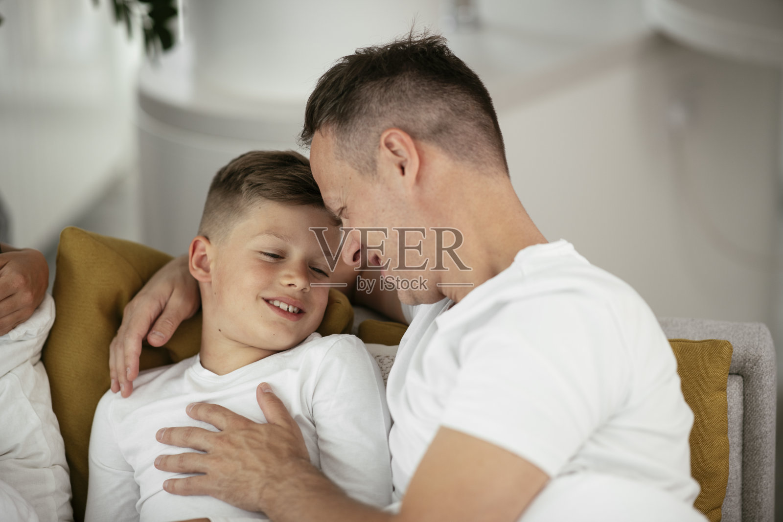 快乐的男人和儿子在床上放松。照片摄影图片