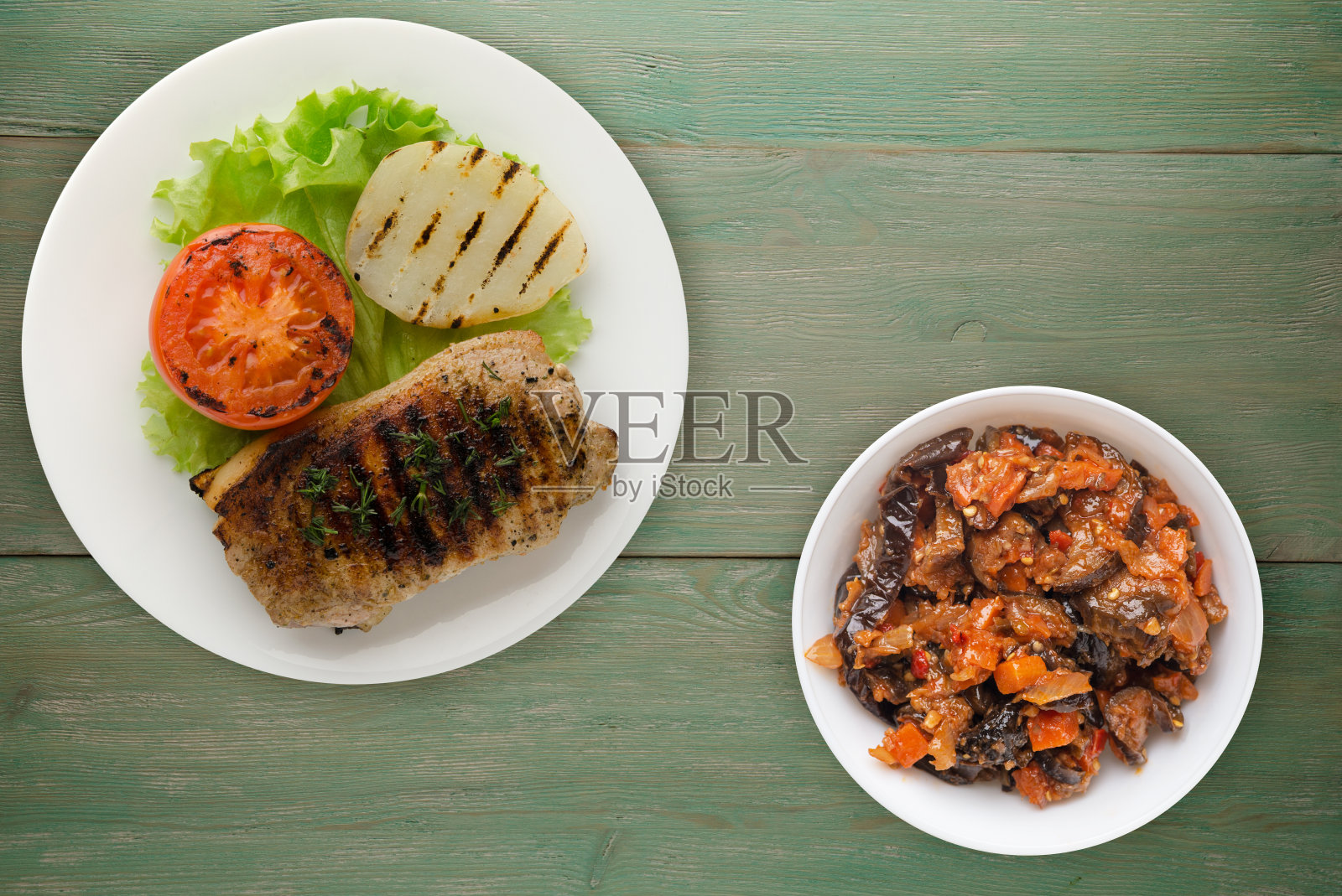 木背景上的土豆和番茄烤猪肉。盘子里的烤猪肉照片摄影图片