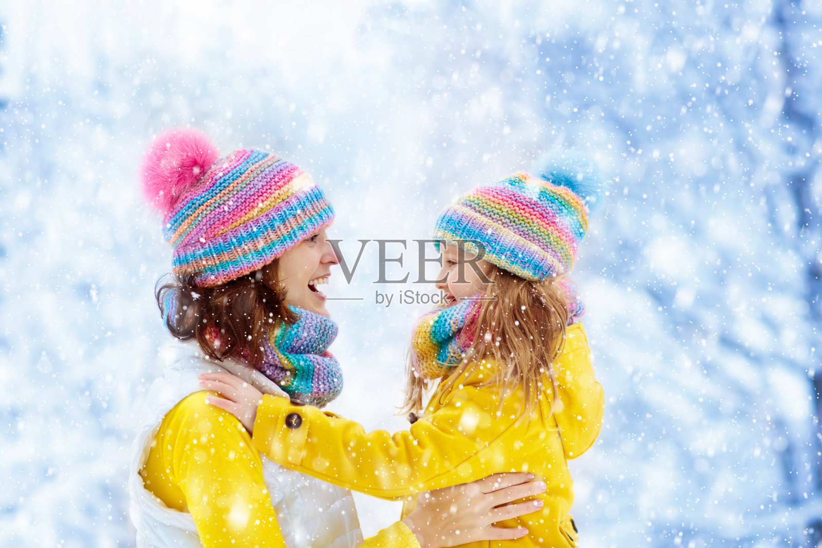 母亲和孩子在雪地里编织着冬天的帽子。照片摄影图片