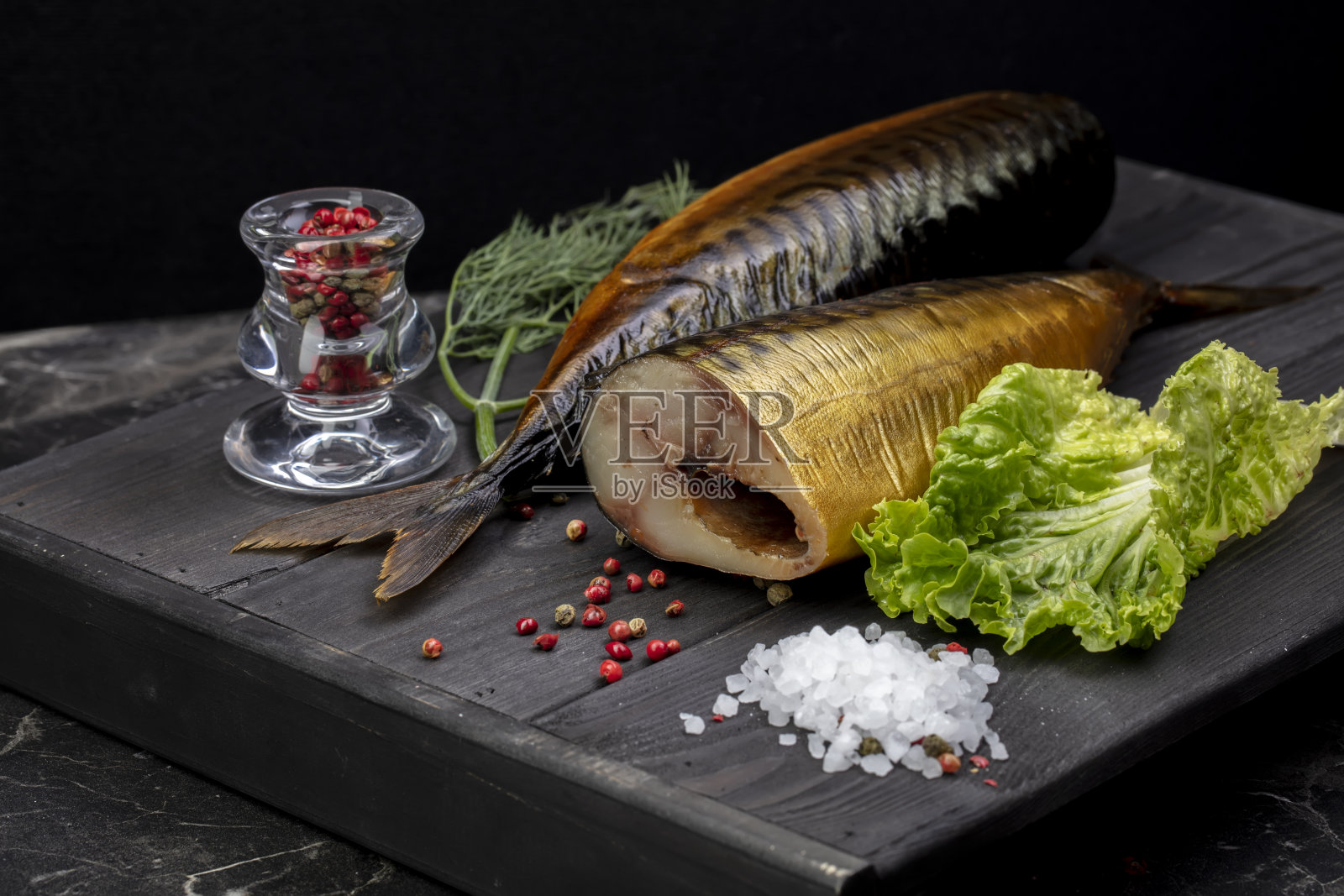 熏鱼和香草放在木板上。美丽的鲭鱼的食物。照片摄影图片