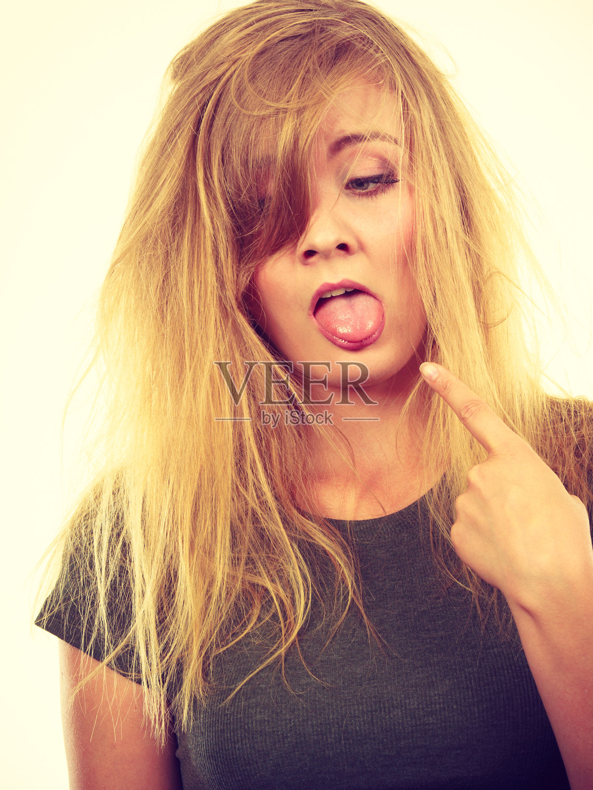 一个头发乱蓬蓬的可怜金发女人指着舌头照片摄影图片