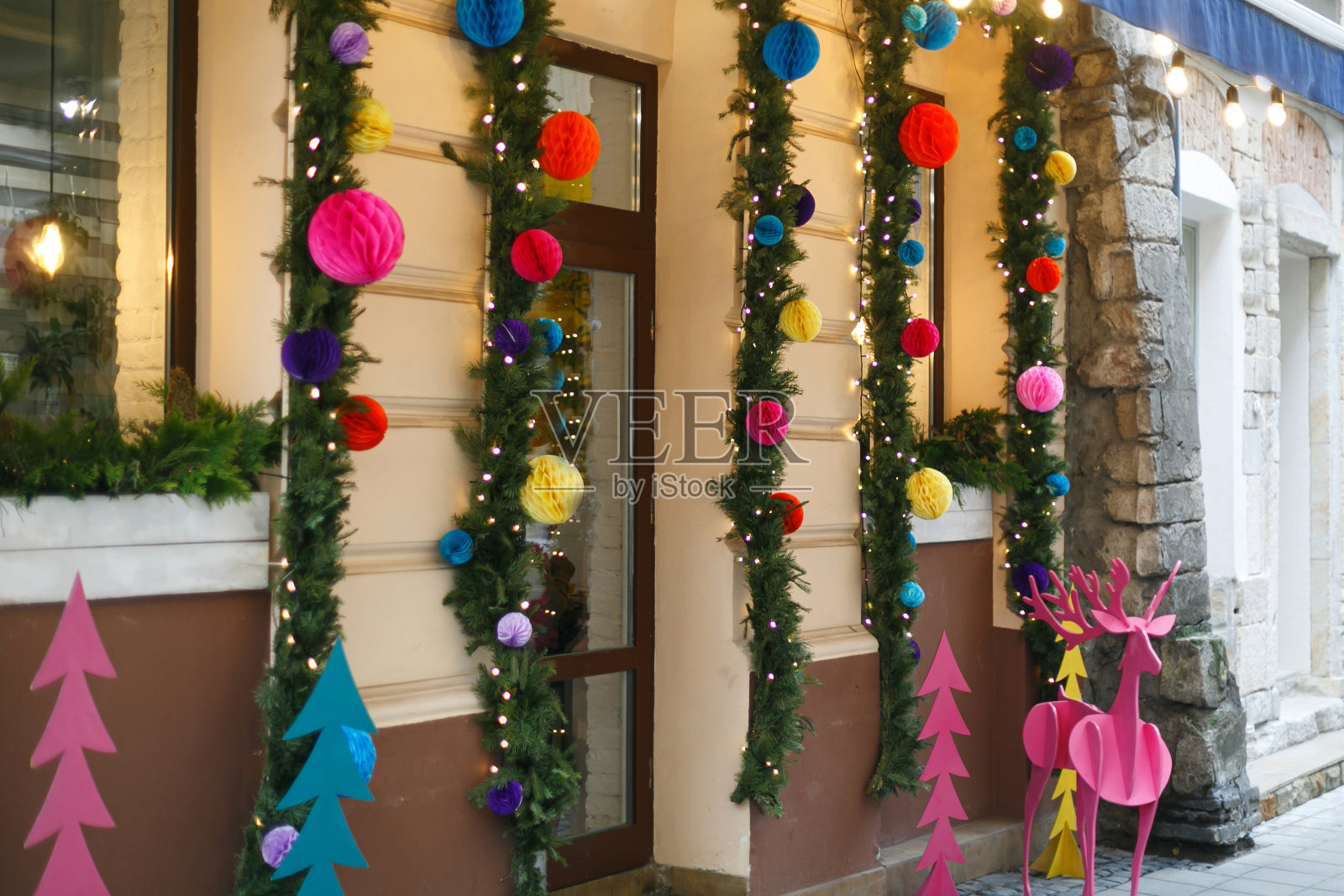 时尚的圣诞树枝，彩色的木制驯鹿和装饰品，现代装饰的店面照片摄影图片