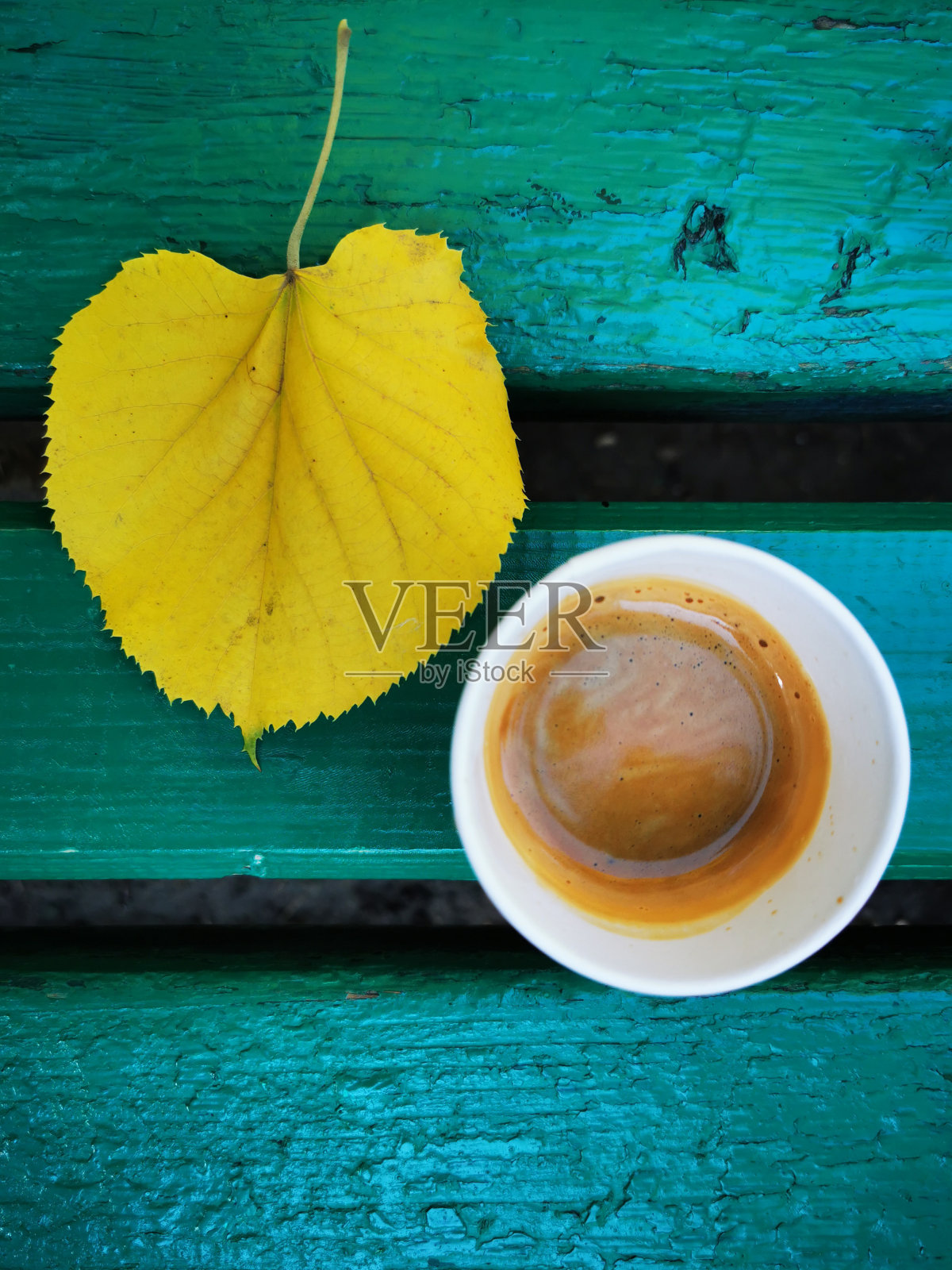 一杯咖啡和黄色的树叶放在木凳上照片摄影图片