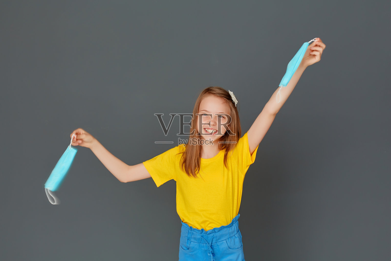 女孩高兴地挥舞着不再需要的口罩，因为隔离已经结束了。深呼吸。新型冠状病毒被击败。医疗保健的概念。照片摄影图片