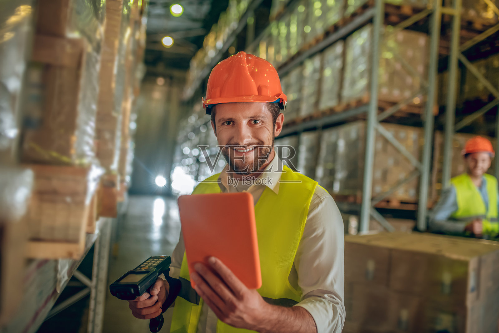 身着黄色背心的仓库工人微笑着拿着平板电脑照片摄影图片