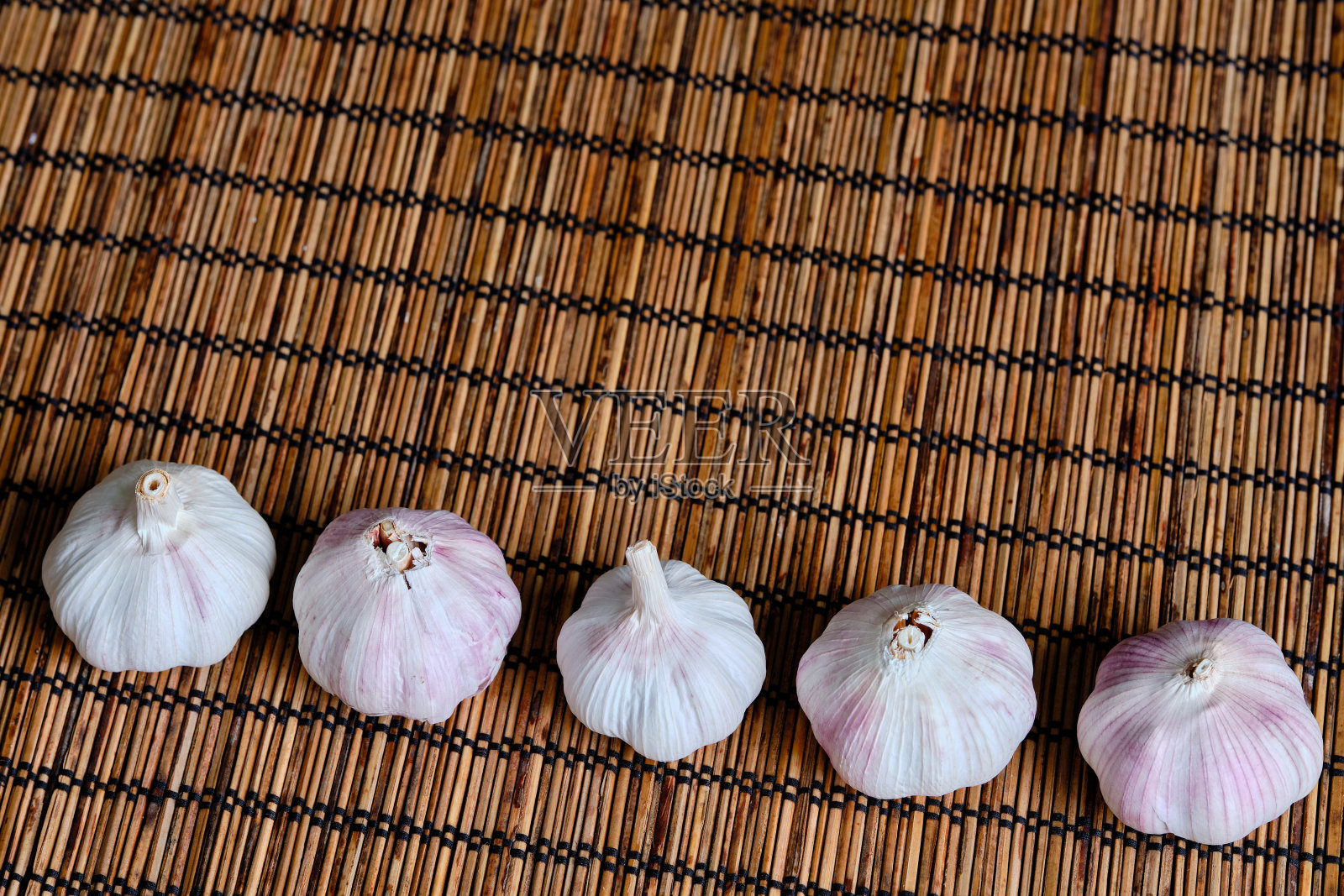 特写一组新鲜的大蒜在竹柳条餐巾的背景排。副本的空间形象。照片摄影图片