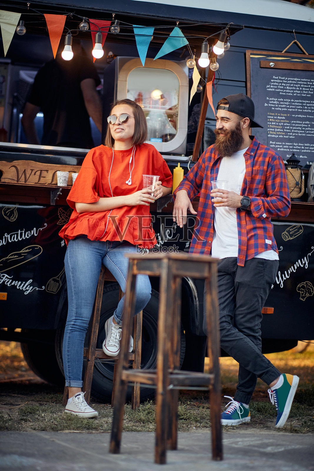 城市的年轻夫妇在卡车前吃快餐，享受夕阳照片摄影图片