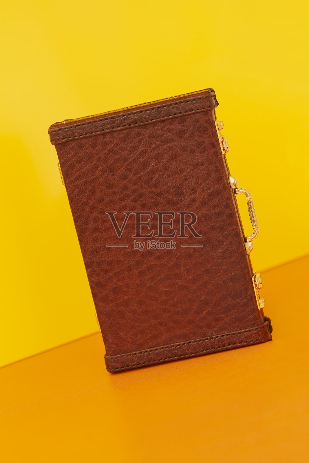 复古的棕色外交公文包与纹理爬行动物，鳄鱼在明亮的黄橙色背景照片摄影图片