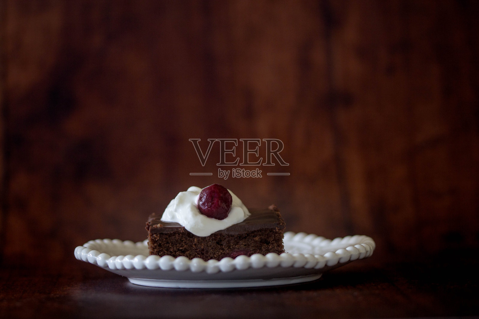 一块巧克力蛋糕，奶油和樱桃照片摄影图片