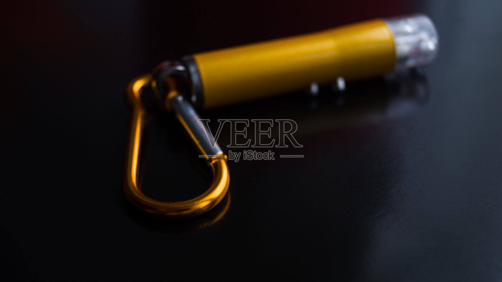 在黑暗背景下具有多种模式的激光指针。激光上的金属卡宾枪。点东西。孩子们的玩具。黄色的小金属手电筒。文本。专注于卡宾枪。照片摄影图片