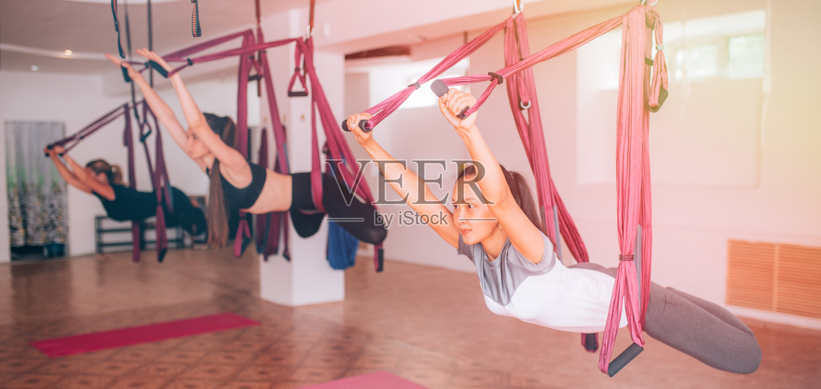 年轻漂亮的女孩在吊床上做飞行瑜伽，健康的生活方式照片摄影图片