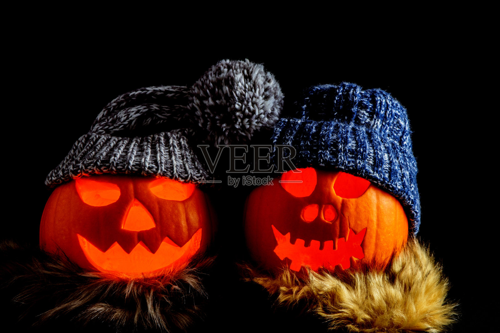 两个万圣节南瓜与羊毛帽子和围巾在一个黑色的背景照片摄影图片