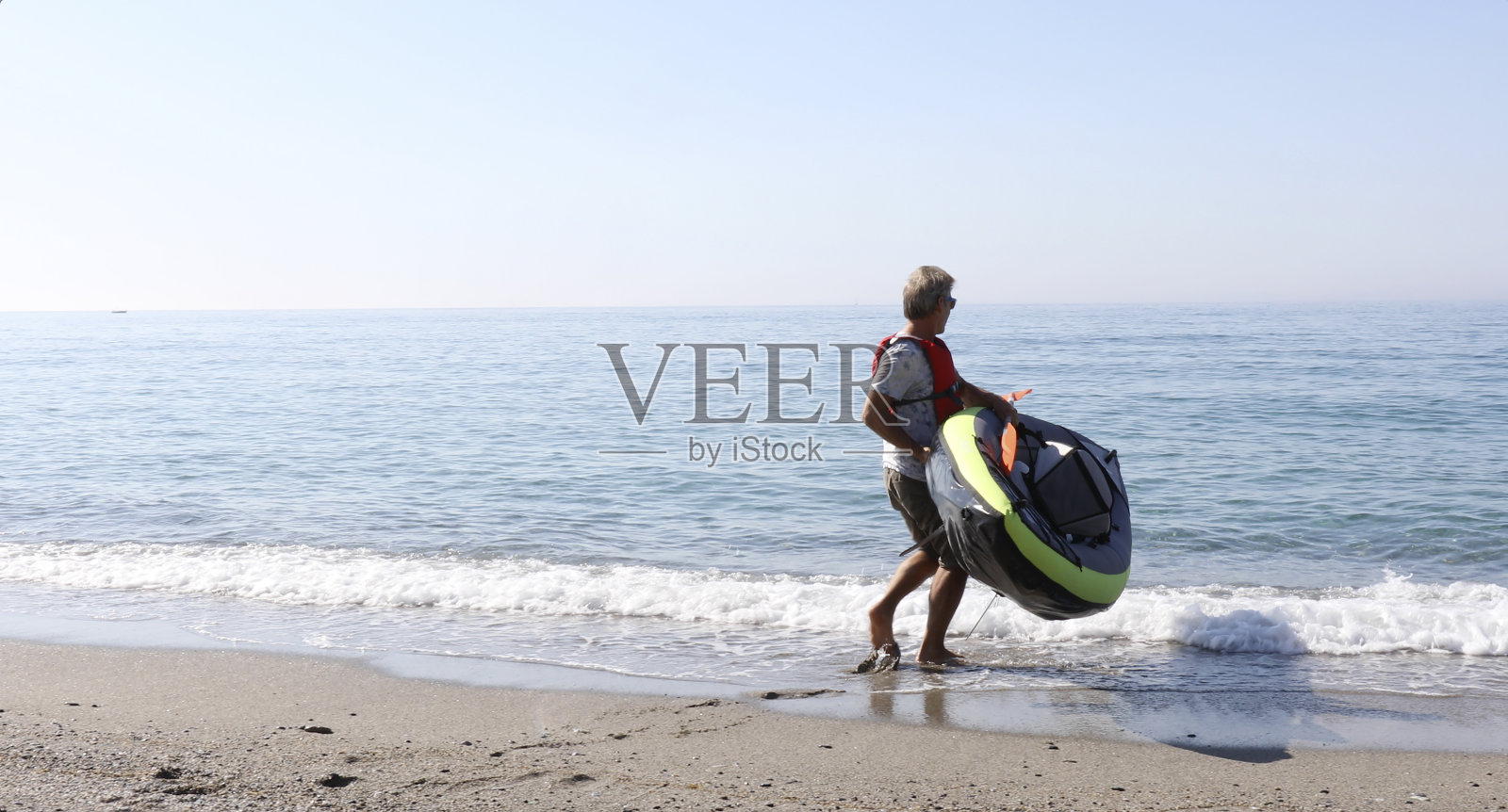 清晨，一名男子带着皮划艇出海照片摄影图片