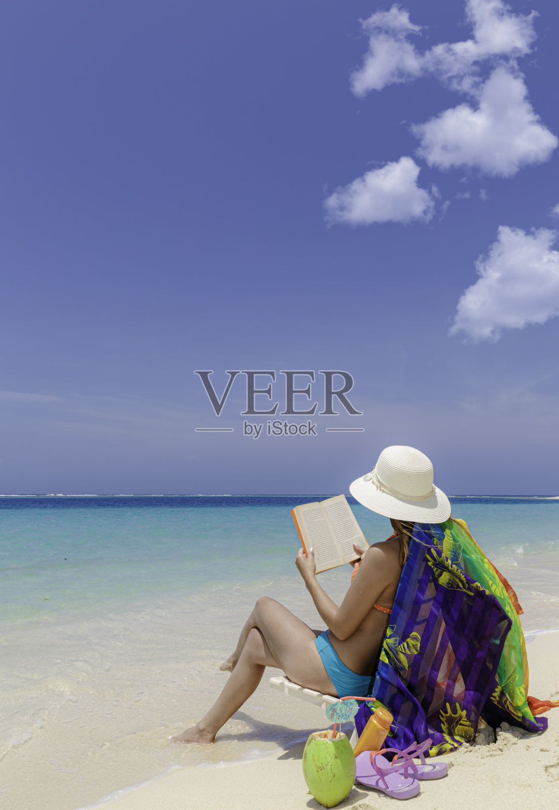 一名西班牙裔年轻女子在加勒比海的一个热带白沙岛上的沙滩上看书照片摄影图片