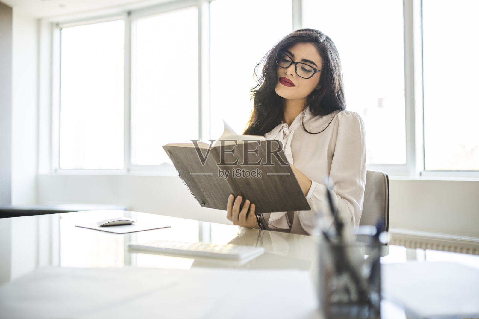 年轻的商业女性在她的办公室里阅读日记，摇摇一天，在电脑上工作照片摄影图片