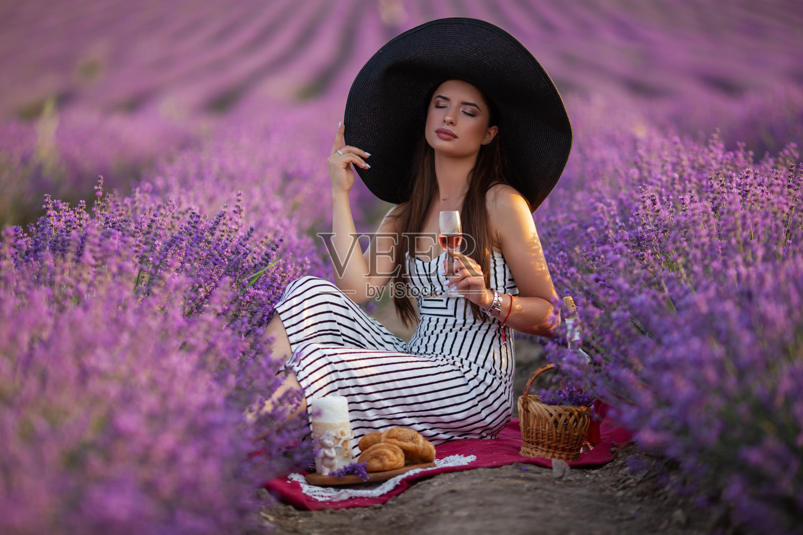 漂亮的女孩戴着大帽子坐在薰衣草田，法国。照片摄影图片