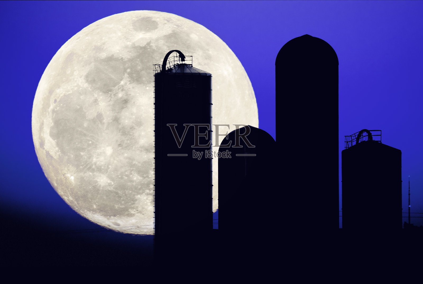 蓝月亮在有四个筒仓的农村家庭农场上空。照片摄影图片