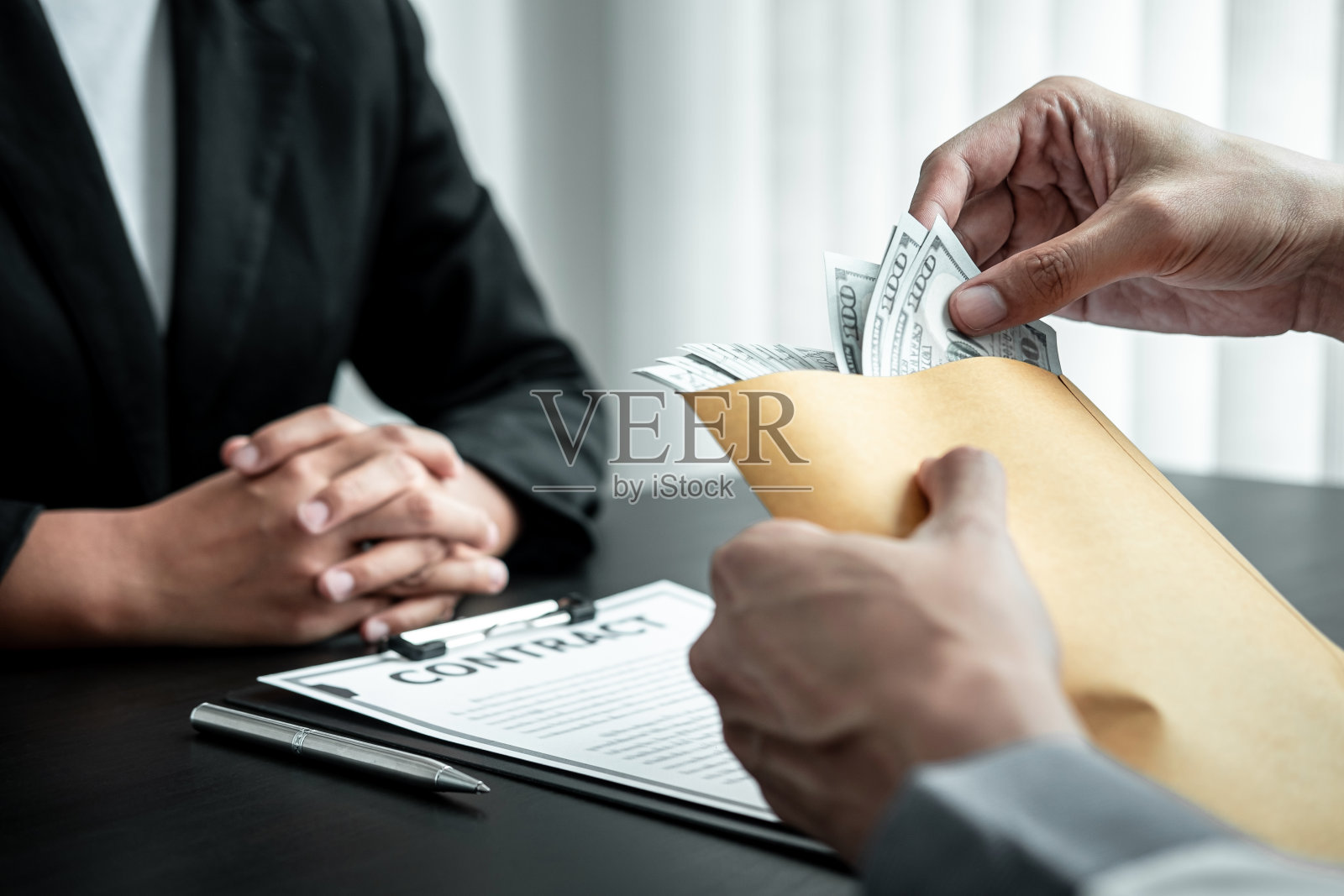 商人将行贿款装在信封中给女商人以贿赂交易合同，属于腐败、非法、不诚实和诈骗行为照片摄影图片