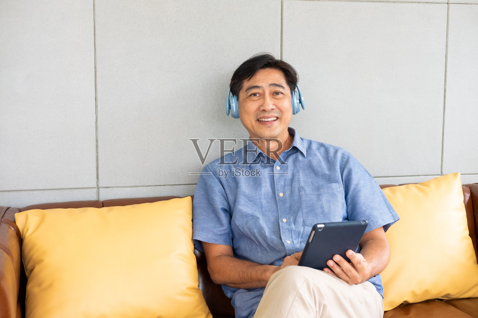 年长的亚洲祖父享受和感觉快乐，从无线耳机听音乐，从智能手机或平板设备流媒体音乐。老年人退休生活方式健康。照片摄影图片