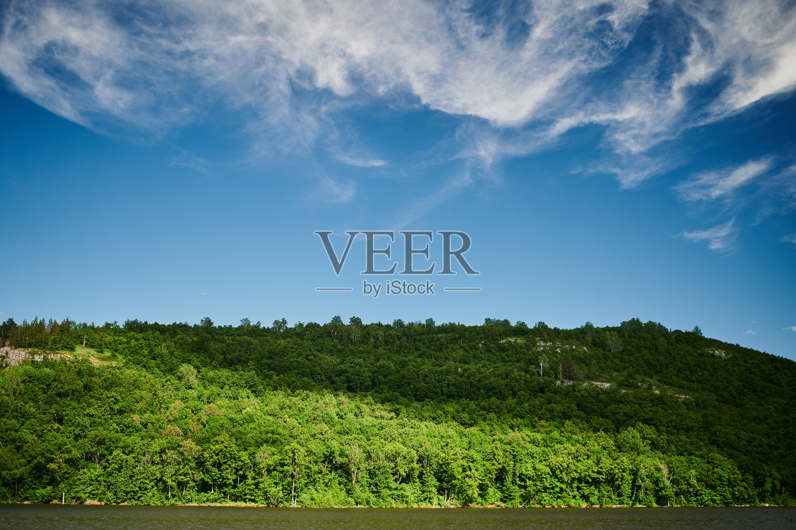 在一个阳光明媚的夏日，绿色的田野在前景和山崖和小山的背景的自然视图。照片摄影图片