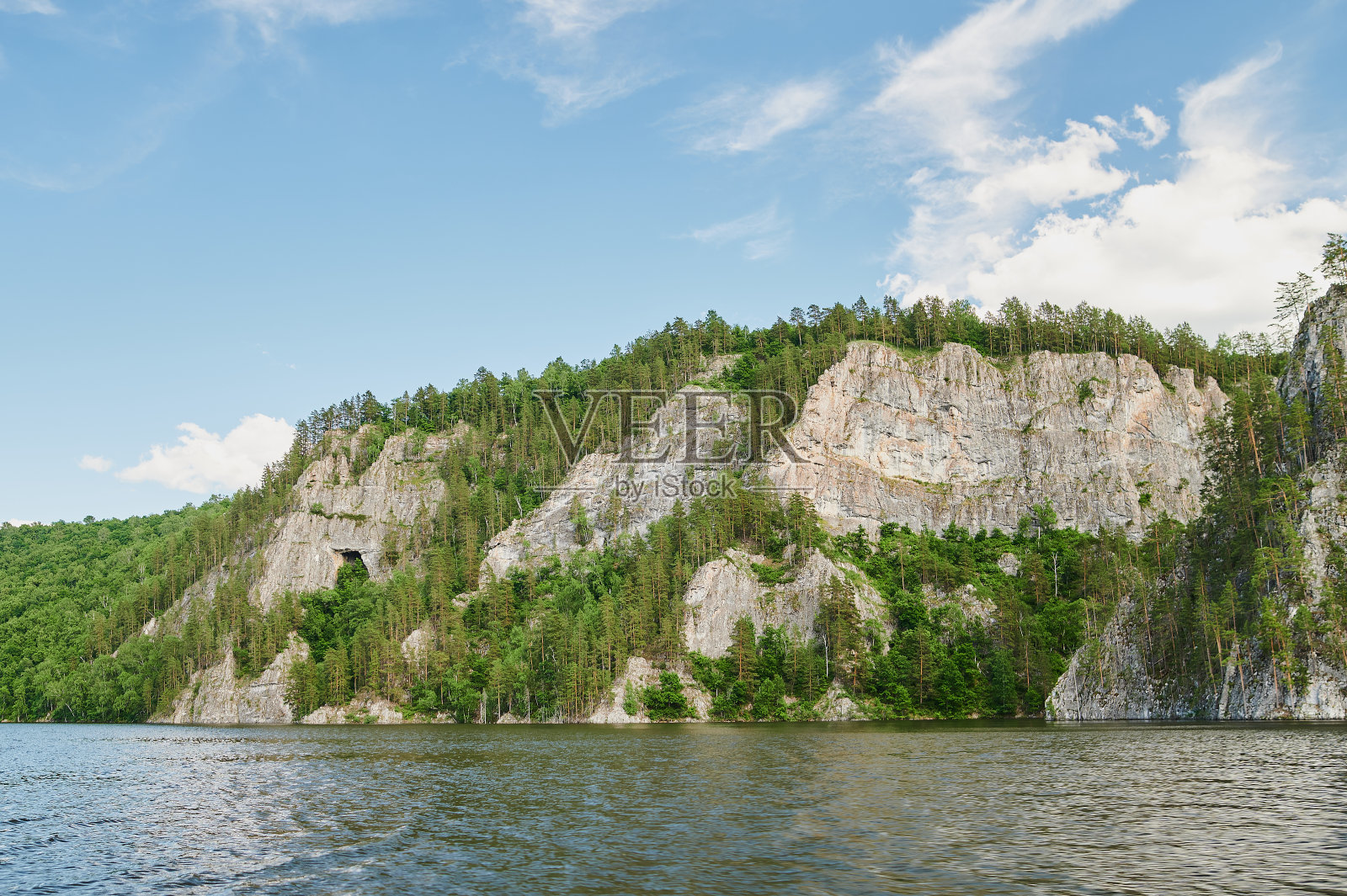 前景中的绿色田野和背景中的悬崖山脉和山丘的自然视图，在一个阳光明媚的夏日。照片摄影图片