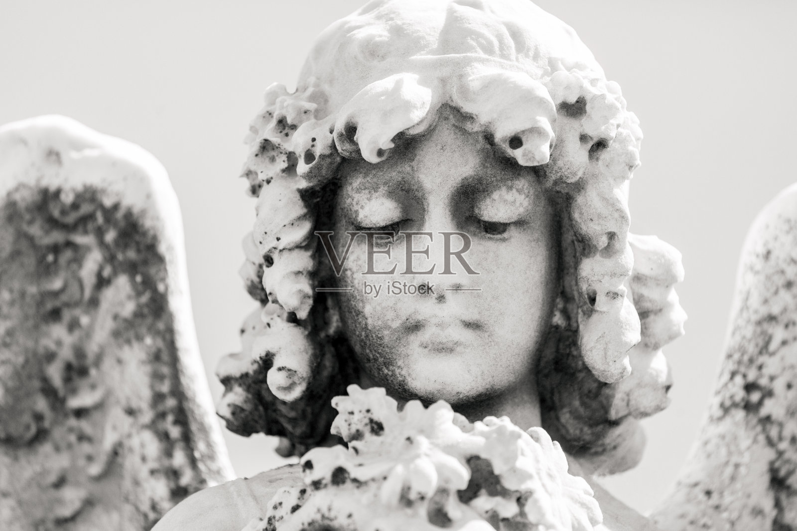 黑白天使的脸，老雕像的角度与花，正面的看法，背景与复制空间照片摄影图片