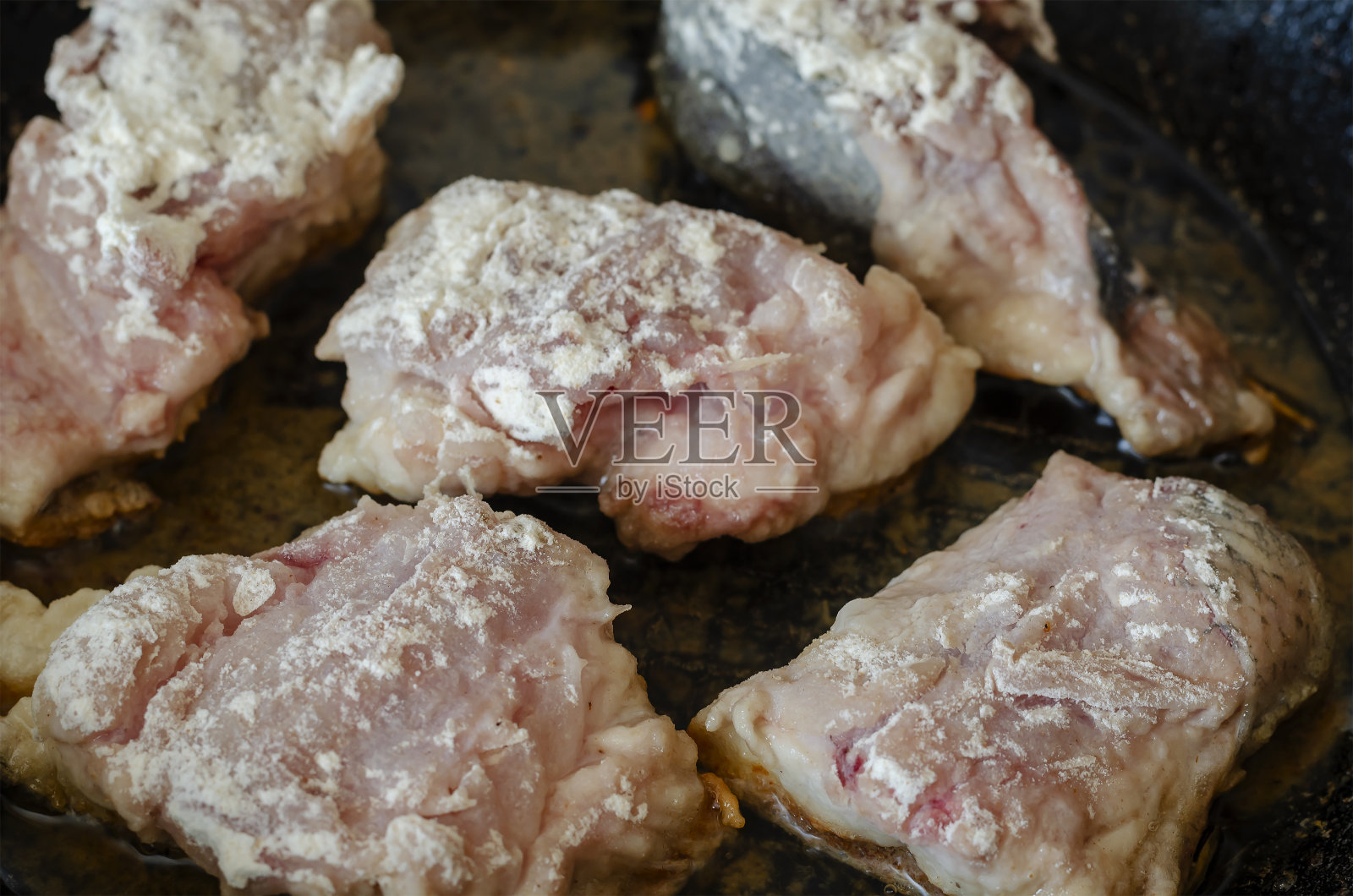 生鱼片在面粉里压碎，放在铸铁的煎锅里炸。照片摄影图片