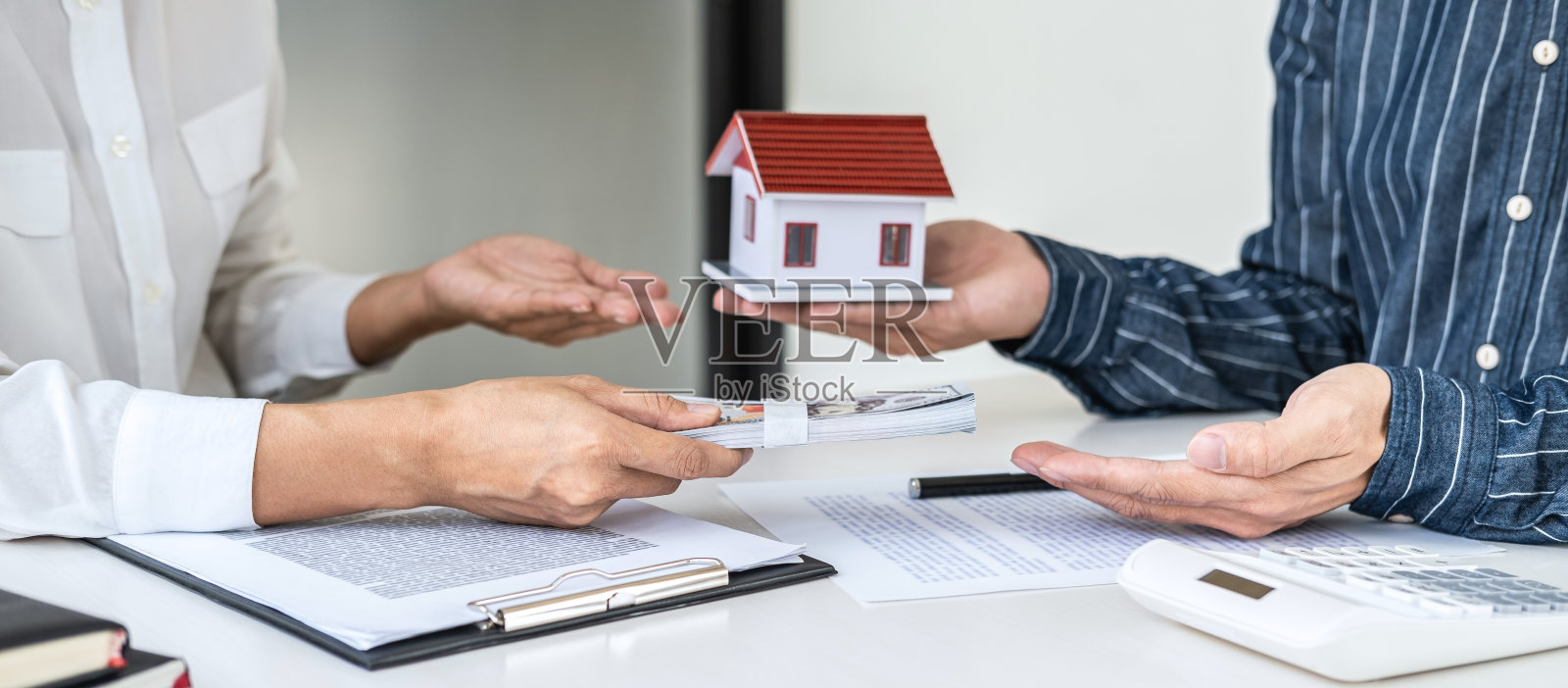 房地产经纪人向客户提交和咨询决策签订保险单协议、房屋模型、有关抵押贷款报价和房屋保险照片摄影图片