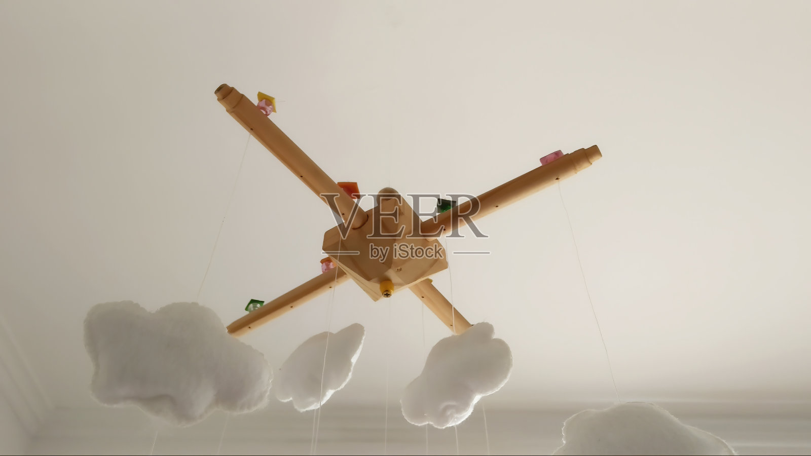 婴儿房移动吊在天花板上，木制底座上有五颜六色的气球和云朵。照片摄影图片