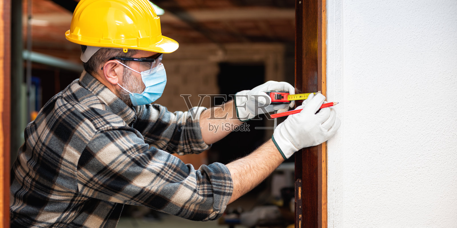 木匠在工作时用外科口罩保护脸部。木工。Covid-19预防。照片摄影图片