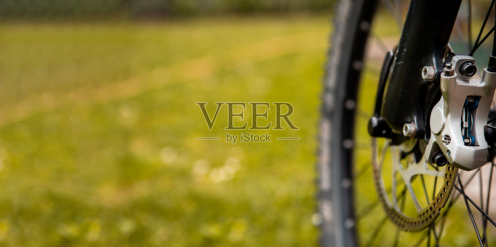 一个山地车刹车系统的特写。见磨损的制动盘和液压制动机构。照片摄影图片