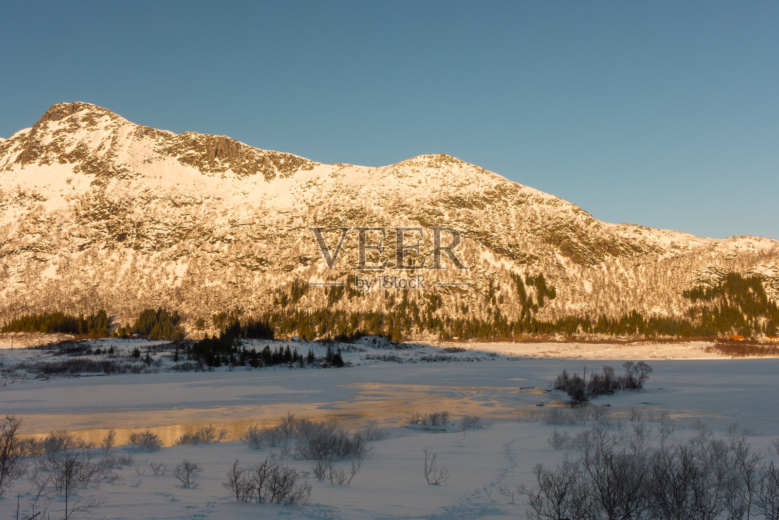 美丽的冬季景观与湖泊和陡峭的山脉附近斯沃瓦尔在罗浮敦群岛在挪威雪与蓝天晴朗的一天照片摄影图片