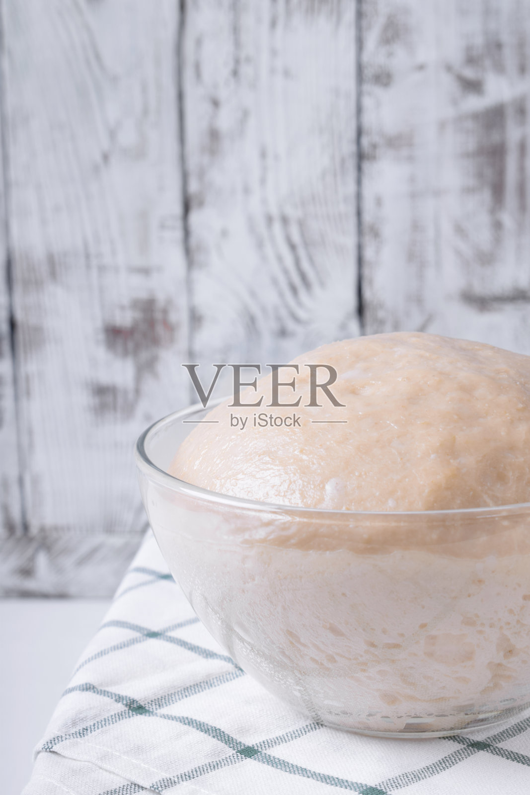 将生面团放入玻璃碗中发酵，准备制成烘焙产品照片摄影图片