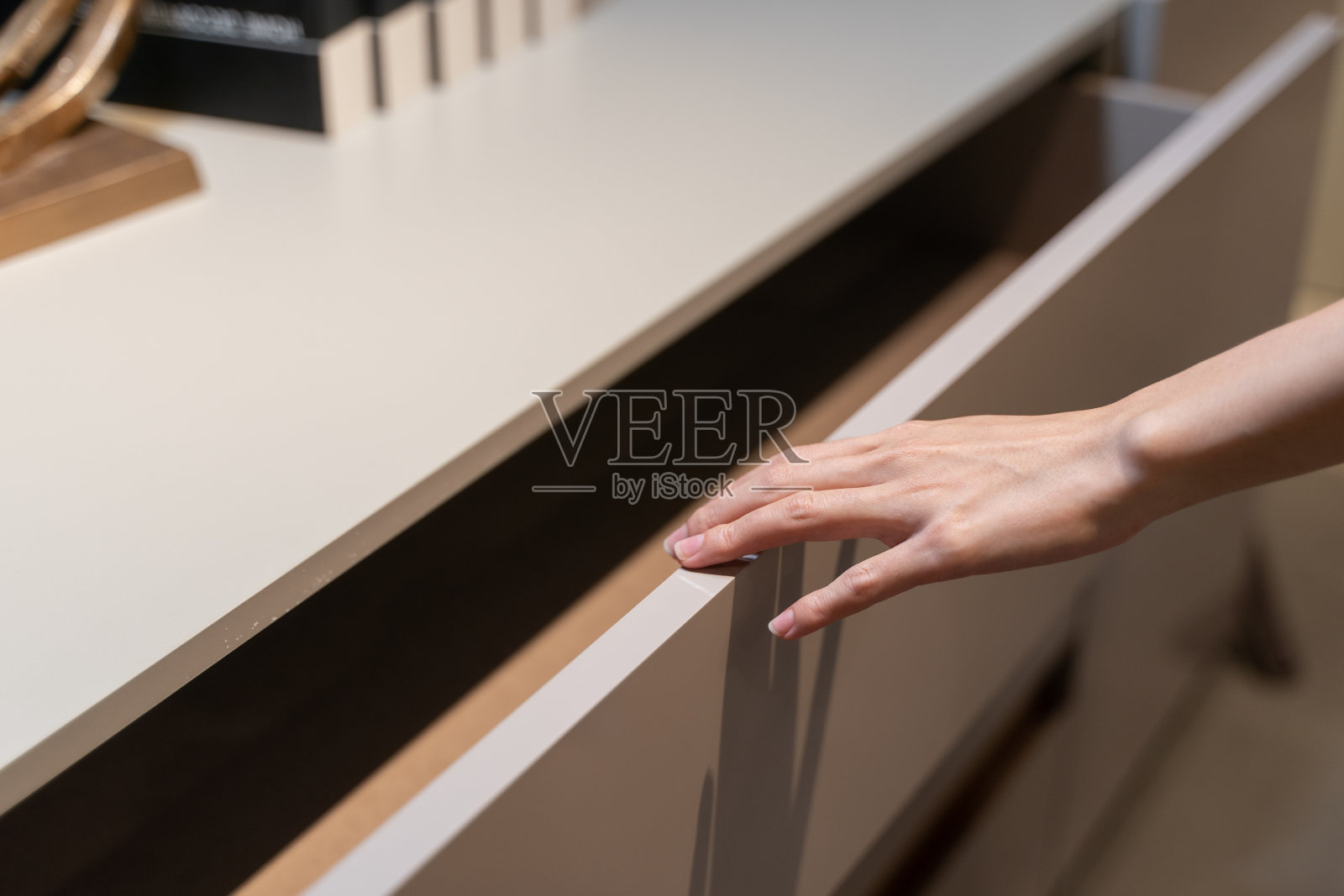 女人打开架子，拉开橱柜里的木抽屉。照片摄影图片