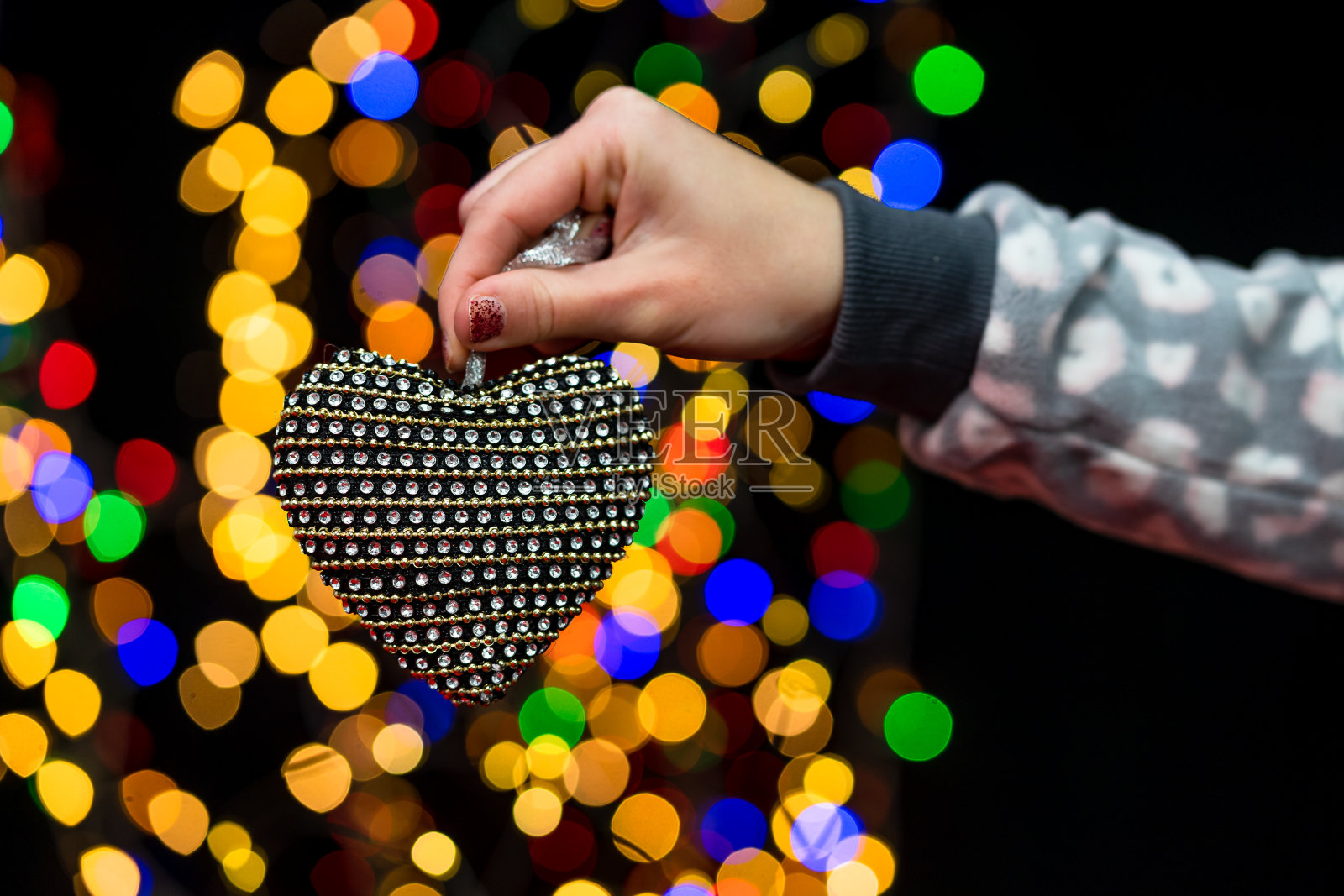 女人的手握着圣诞装饰。圣诞和新年假期背景，冬季圣诞装饰和模糊的灯光照片摄影图片