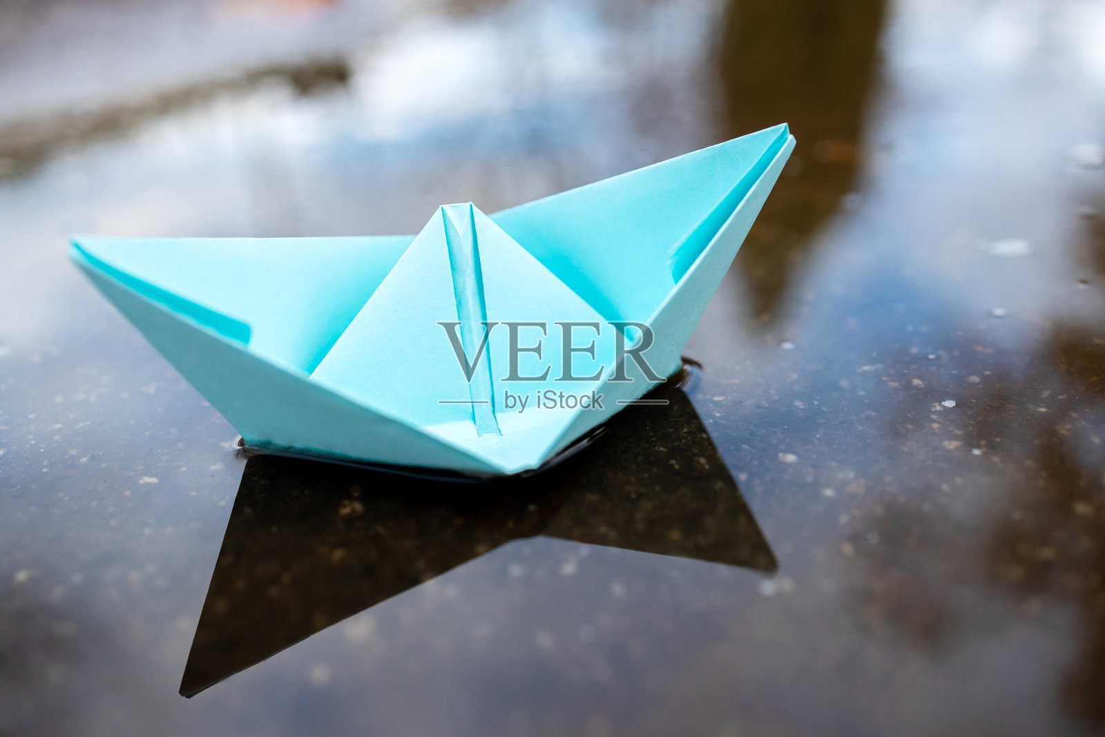 一艘蓝色的纸船漂浮在水面上。在户外。秋天的季节。带有副本空间的贺卡。领导的概念。自由的概念照片摄影图片