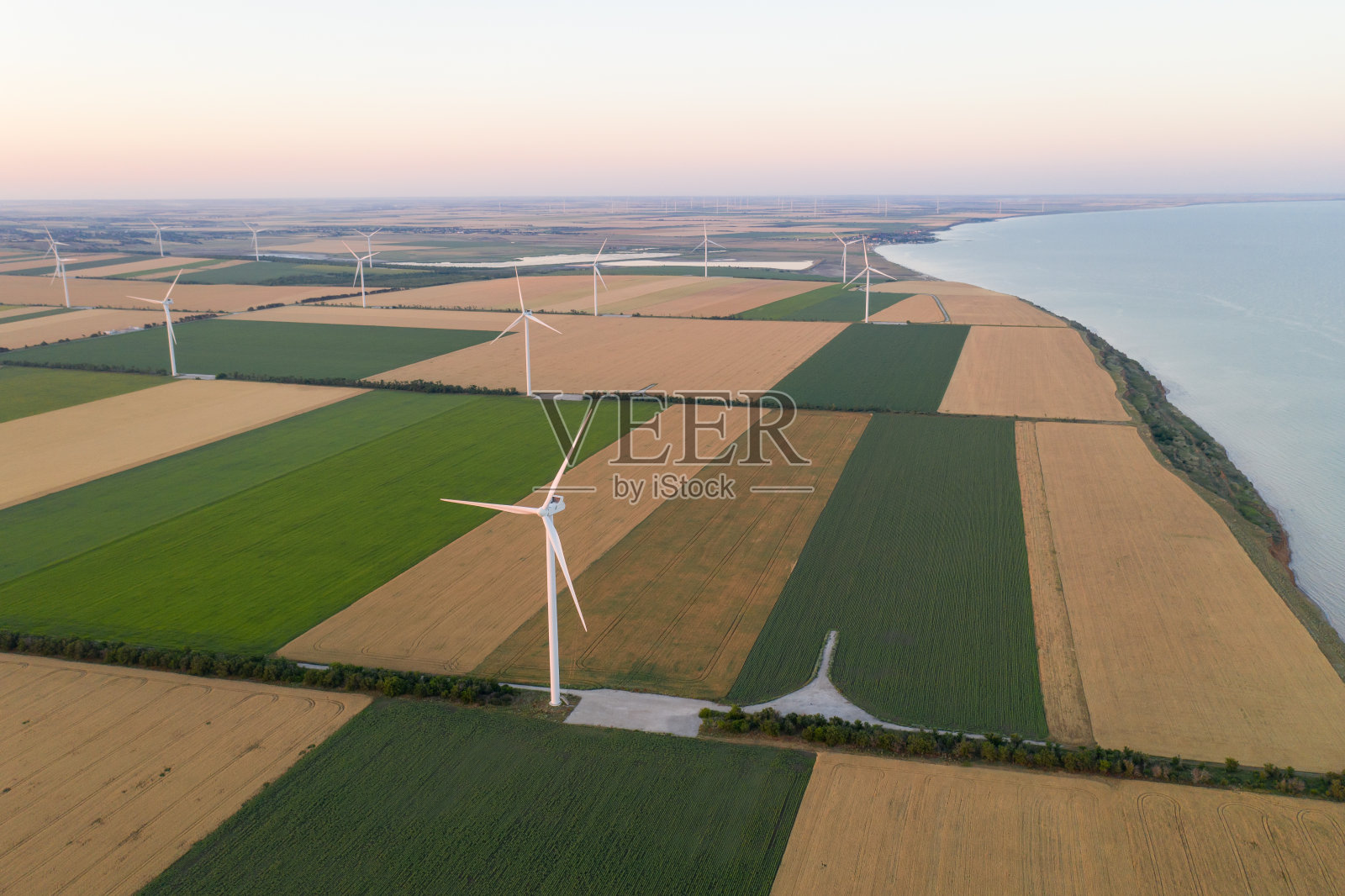 风车上的日落。风力涡轮机掠过麦田和向日葵田照片摄影图片
