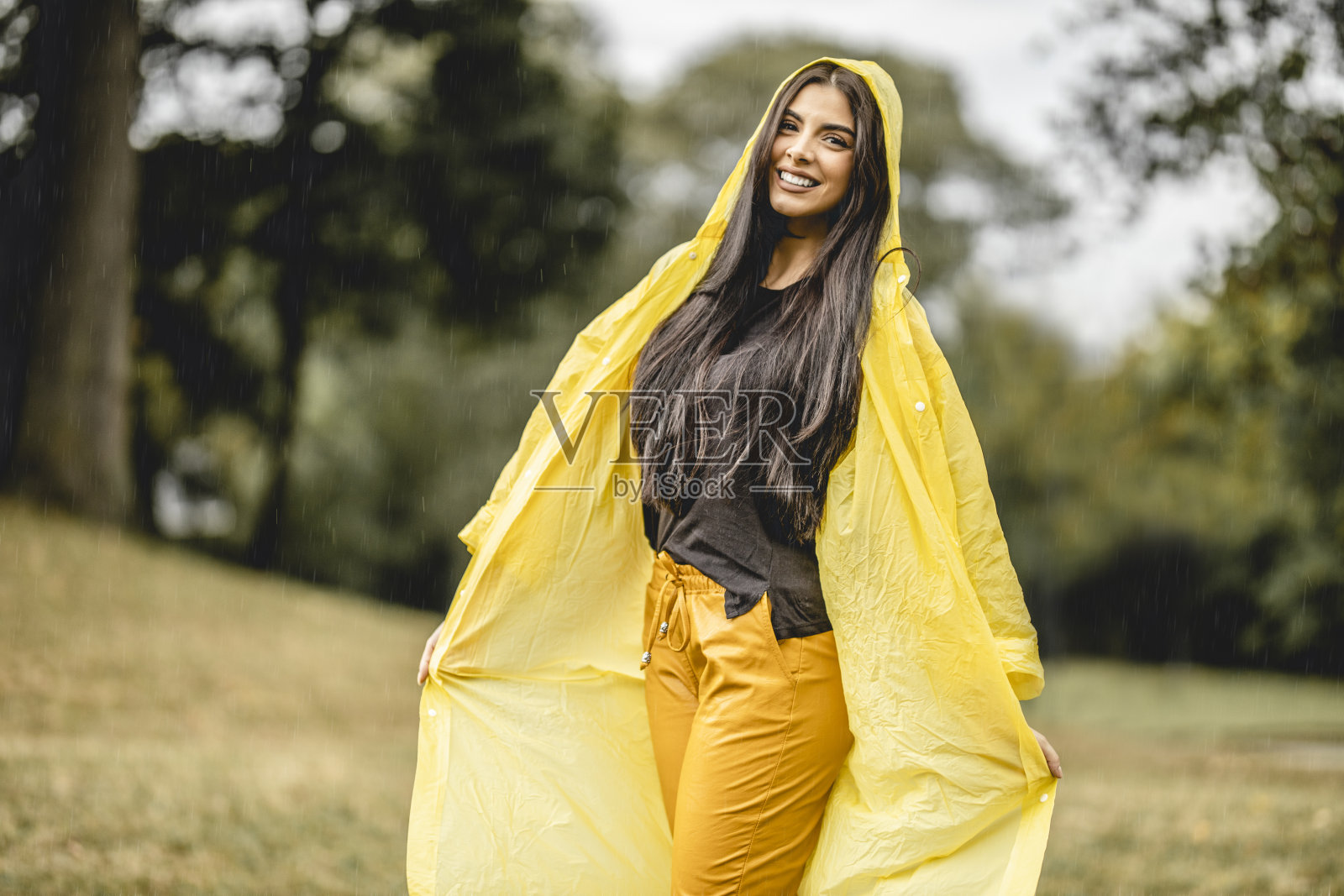 快乐年轻美丽的女人有乐趣，而在雨中跳舞在大自然照片摄影图片