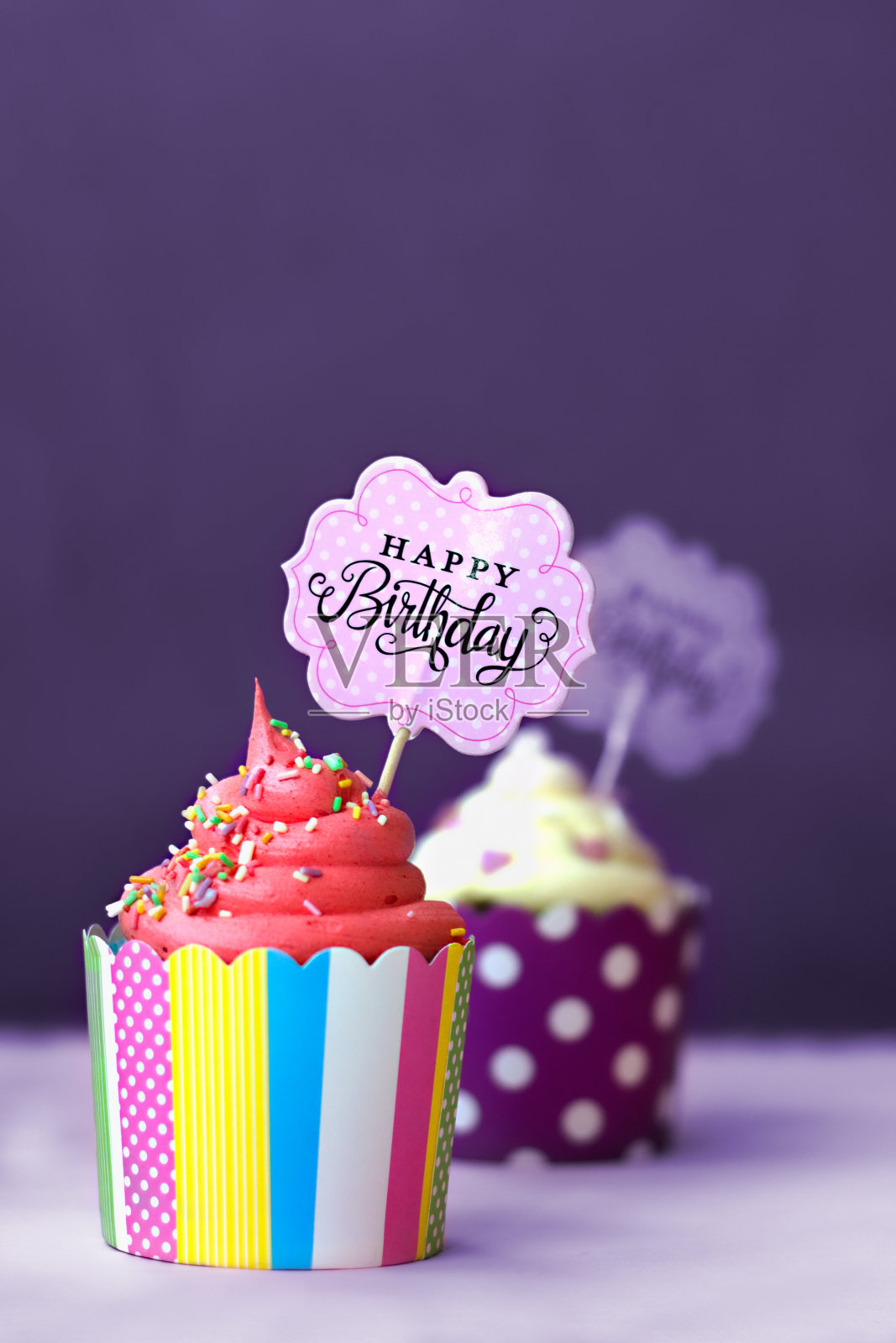 紫罗兰色的背景衬托着草莓香草蛋糕，上面装饰着小心形和生日快乐标志;政党背景照片摄影图片