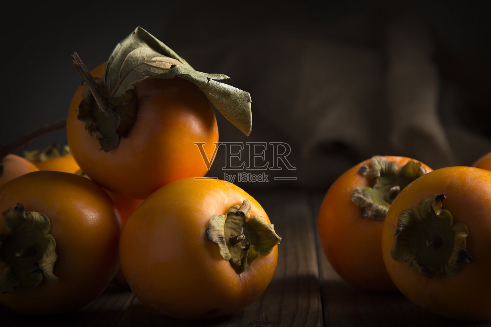 在棕色木桌上低调地摆着卡基斯和柿子的静物画照片摄影图片