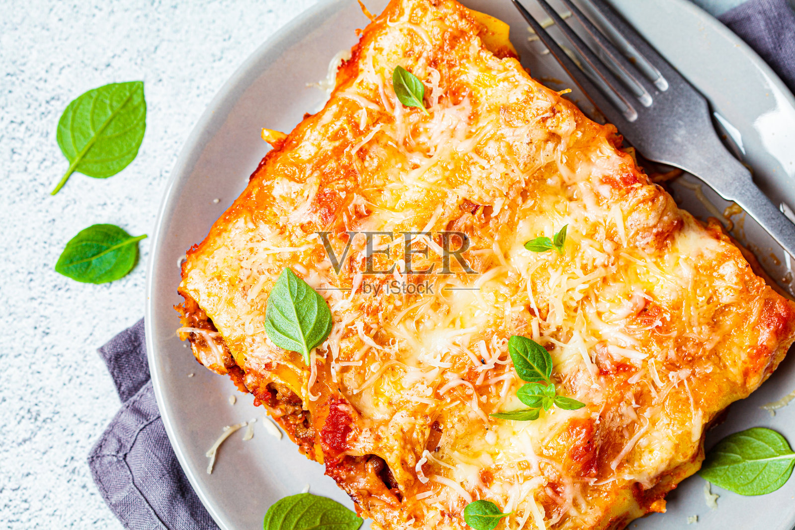 灰色的盘子上放有肉、番茄酱和奶酪的一份cannelloni，灰色的背景，俯视图。意大利美食的概念。照片摄影图片