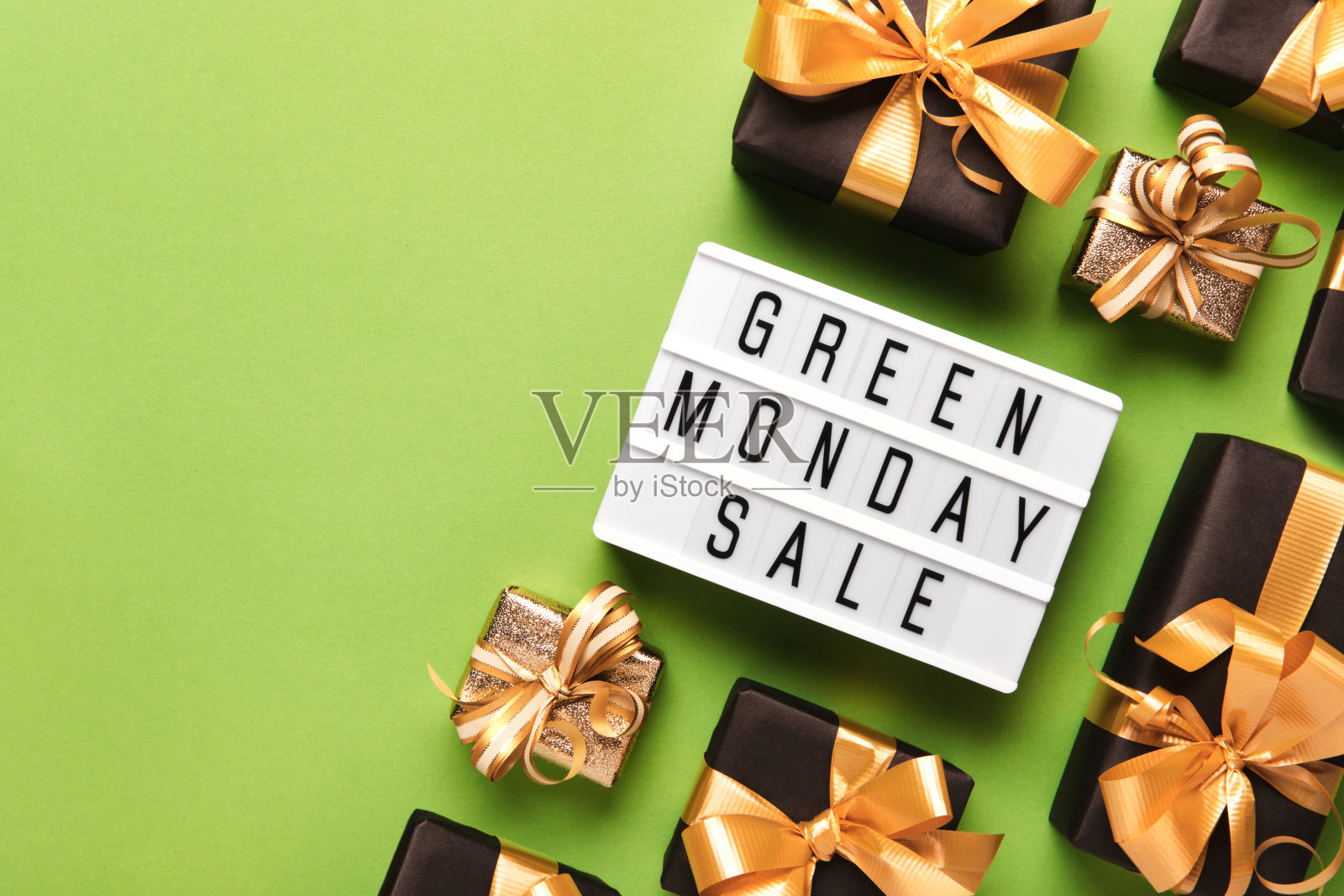 灯箱与绿色星期一销售文字和滚黑色礼盒在绿色纸的背景，拷贝空间照片摄影图片