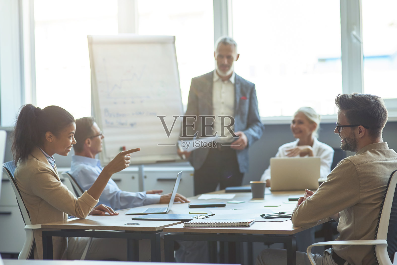 两个不同的办公室工作人员交谈和微笑，与同事在现代办公室开会，成熟的商人提供的背景照片摄影图片