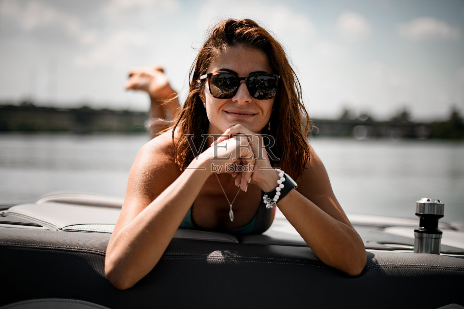 年轻女子的肖像与棕色头发在泳衣和太阳眼镜谁是日光浴照片摄影图片