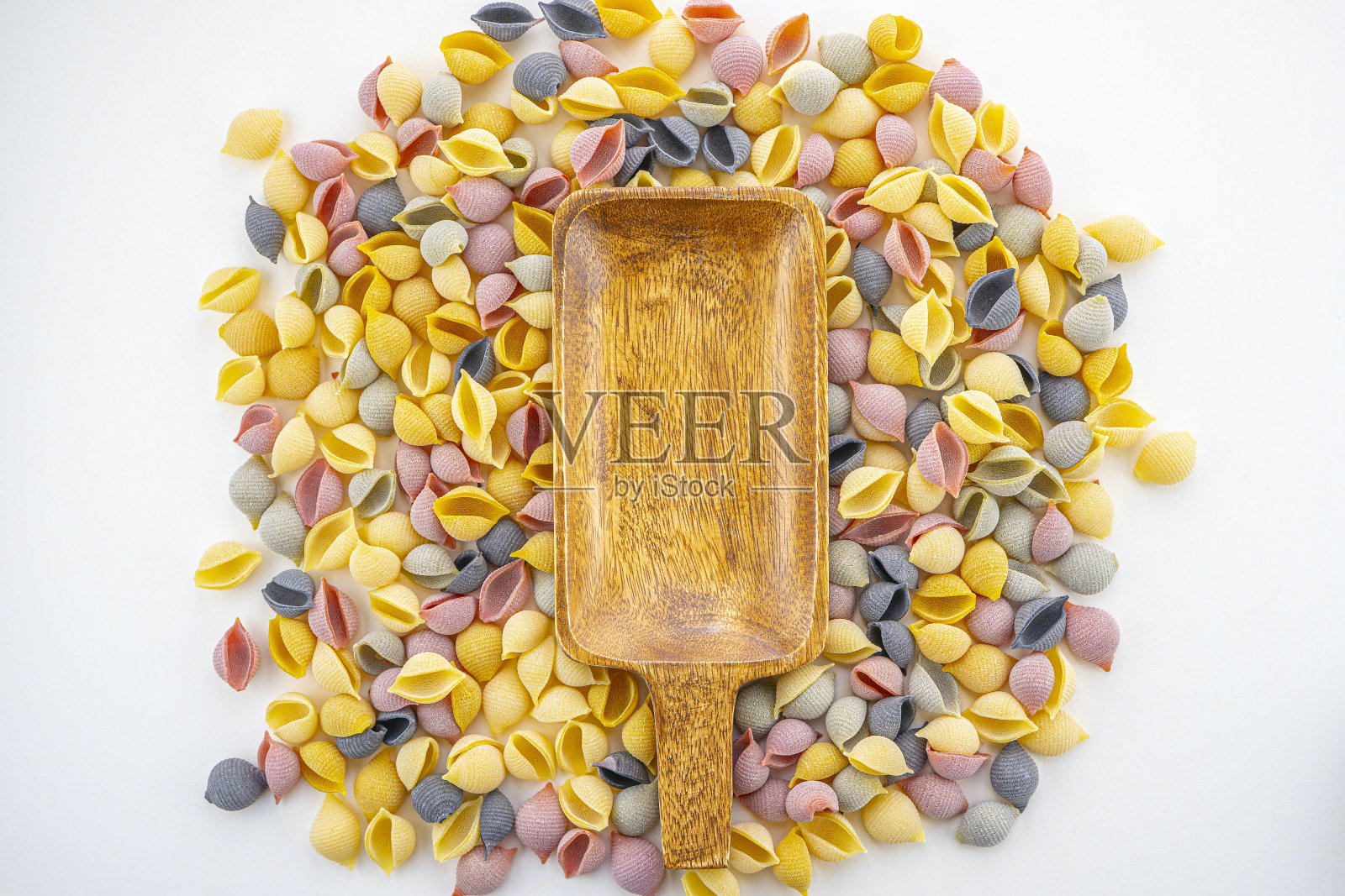 海贝形的意大利生彩色意大利面，有黄、粉、紫三种颜色，有波浪的意大利面围绕在一个木制盘子里。传统的意大利美食。选择性聚焦，复制空间照片摄影图片