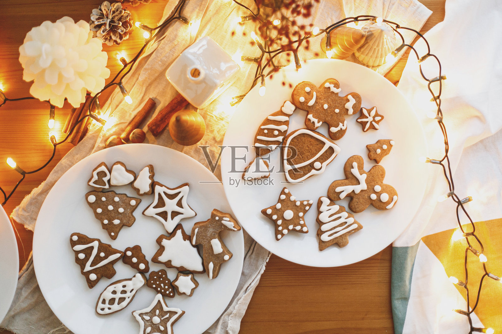 姜饼配糖衣饼干放在木桌上，配上喜庆的彩灯，时间大气。平躺照片摄影图片