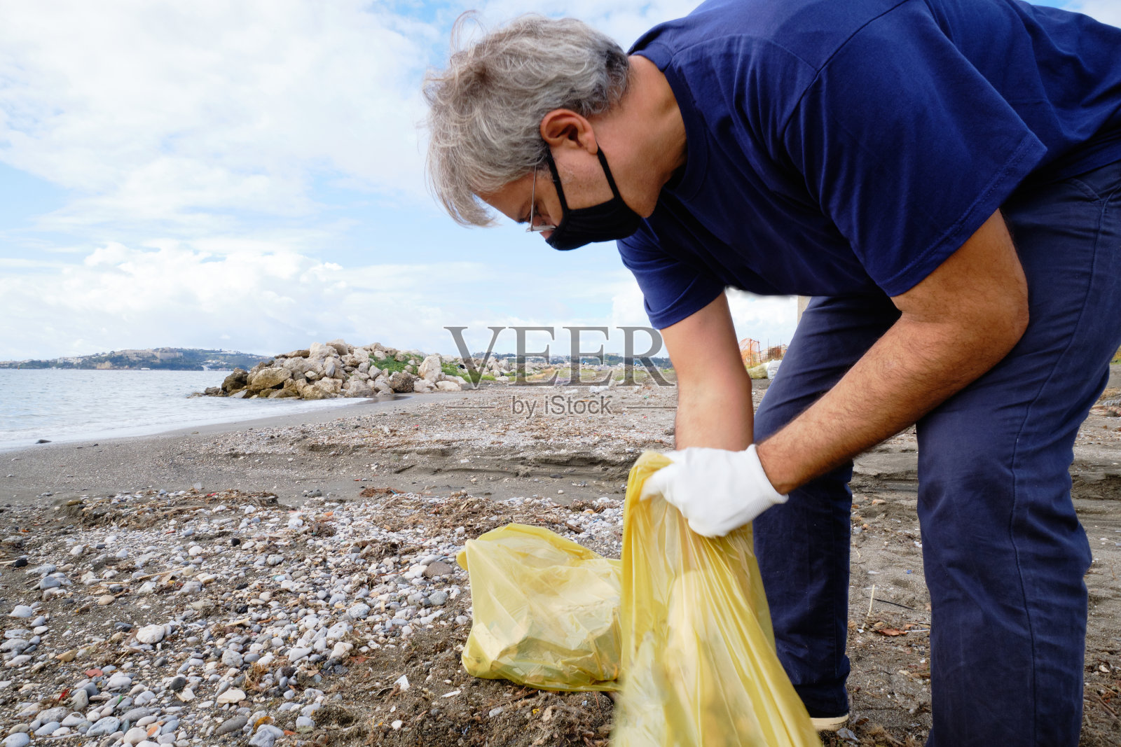 一名男子正在清理意大利海滩上的塑料垃圾照片摄影图片