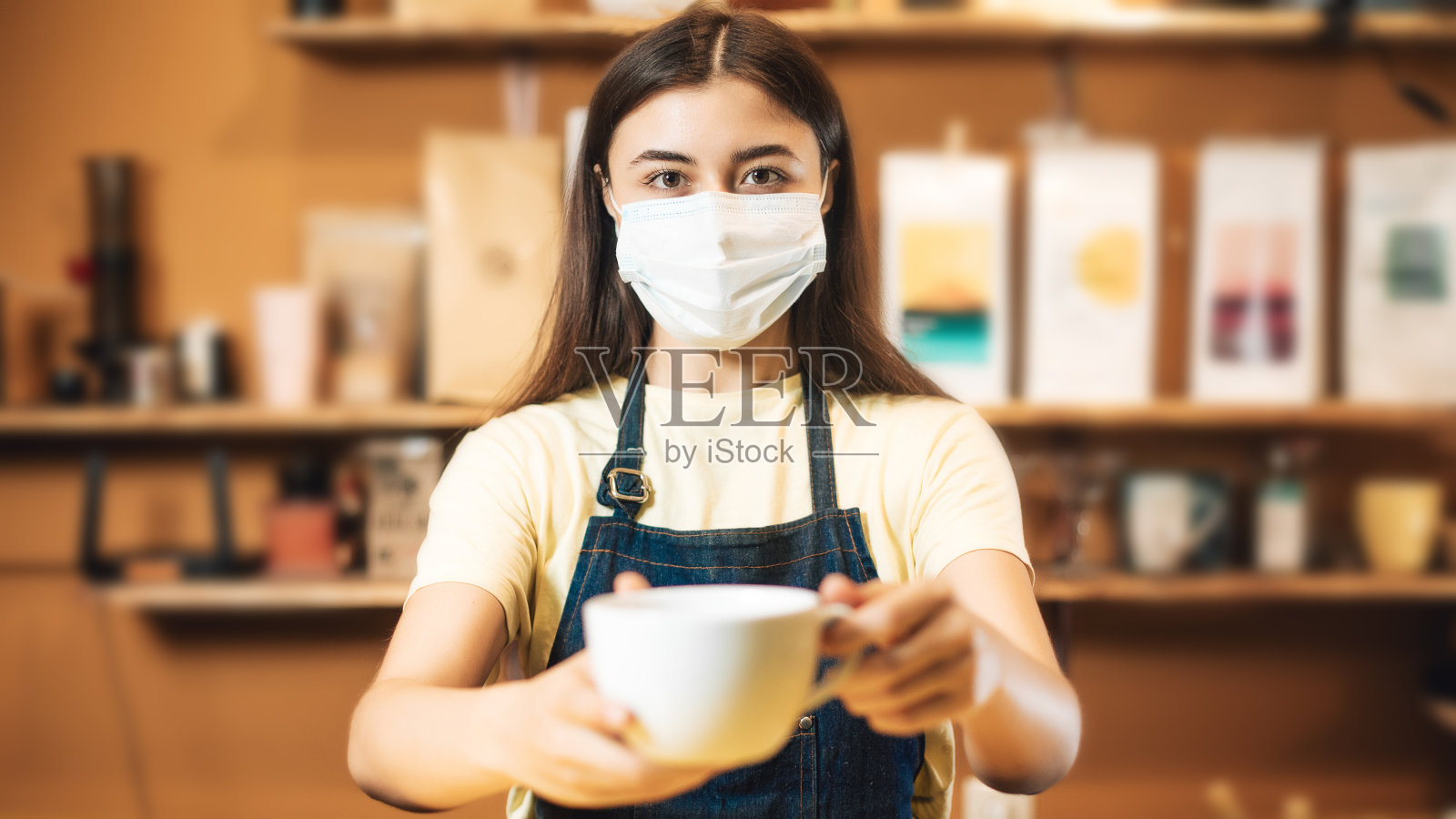 女咖啡师戴着医用防护口罩在室内为客户制作饮料照片摄影图片