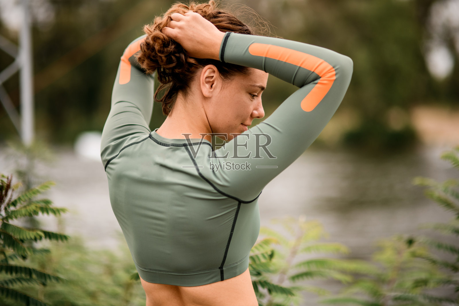 年轻女子用手挽着头发。照片摄影图片